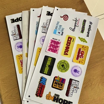 Printed sticker sheets spread across a wooden table.